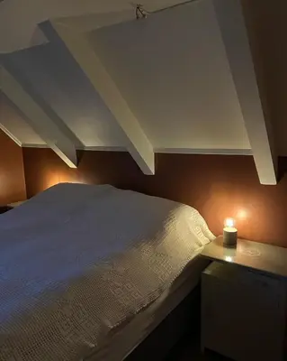 a bedroom with a white bed and a candle on a night stand at Sjarmerende hus med veldig stort uteareal. in Brekstad
