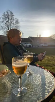 a man sitting at a table with two wine glasses at Sjarmerende hus med veldig stort uteareal. in Brekstad