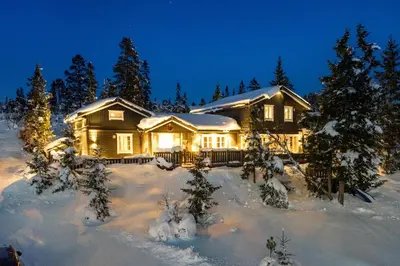 a house in the snow with lights on at Budor - Løvsangeren 7 - 60 min OSL - Badstu - Badestamp - 7 Soverom3 bad in Nordset
