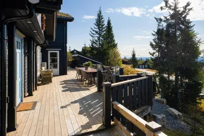 a deck with a table and chairs on a house at Budor - Løvsangeren 7 - 60 min OSL - Badstu - Badestamp - 7 Soverom3 bad in Nordset