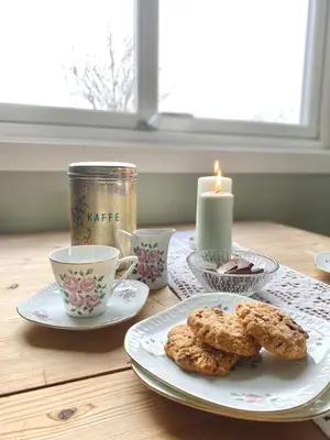 a table with cookies and cups and a candle at Stort og autentisk hus i Skjåk - kort vei til Lom! in Skjåk
