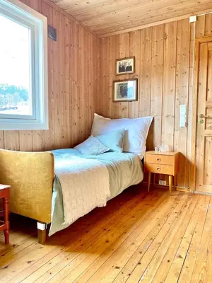 a bedroom with a bed and a window and a chair at Stort og autentisk hus i Skjåk - kort vei til Lom! in Skjåk