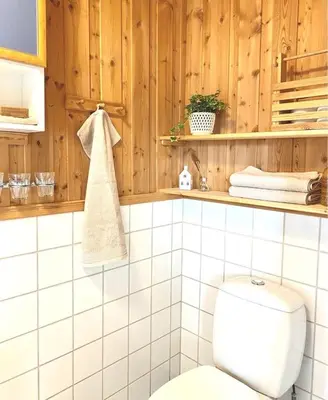 a bathroom with a white toilet and wooden walls at Stort og autentisk hus i Skjåk - kort vei til Lom! in Skjåk