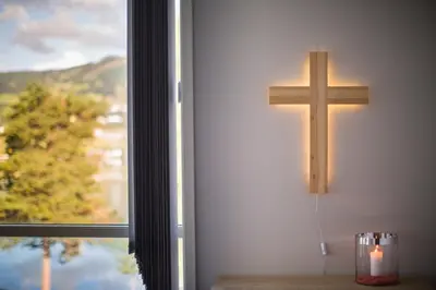 a cross hanging on a wall next to a window at Lyngmo Gjestehus in Hafslo