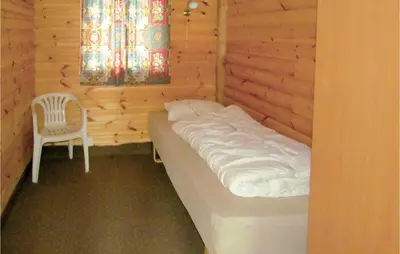 a bed in a wooden room with a chair at Holiday Home Bjoa Haugsgjerdet in Utbjoa