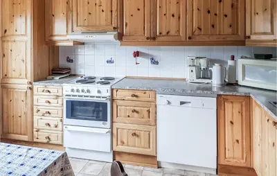 a kitchen with white appliances and wooden cabinets at Ytre Matre in Hamre