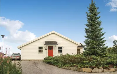 a white house with a red door and a pine tree at Amazing Home In Auklandshamn With Sauna in Vestvik