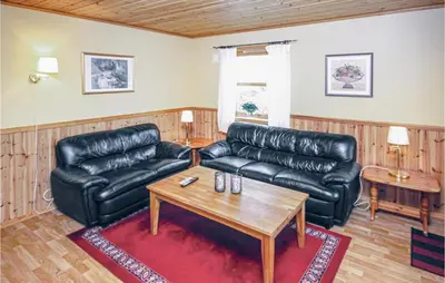 a living room with a leather couch and a coffee table at Amazing Home In Auklandshamn With Sauna in Vestvik