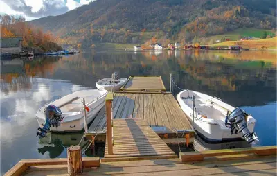 two boats are docked at a dock on a lake at Vågen 1 in Åkra