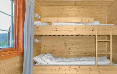 two bunk beds in a wooden room with a window at Vågen 1 in Åkra