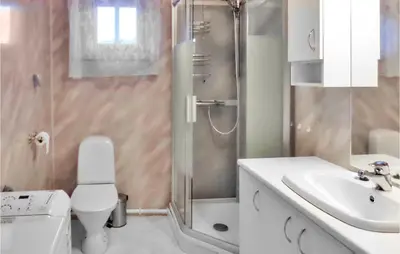 a bathroom with a shower and a toilet and a sink at Vågen 1 in Åkra