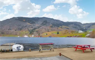 a dock with two picnic tables and a boat on a lake at Vågen 1 in Åkra