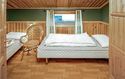 a bedroom with a bed and a chair and a window at 4 Bedroom Cozy Home In Auklandshamn in Vestvik