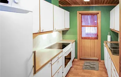 a kitchen with white cabinets and green walls at 4 Bedroom Cozy Home In Auklandshamn in Vestvik