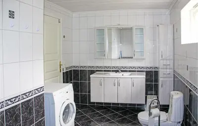 a white bathroom with a sink and a washing machine at Galanten in Grimsland
