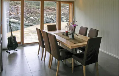 a dining room with a wooden table and chairs at 3 Bedroom Awesome Home In Mosterhamn in Mosterhamn