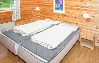 two beds sitting in a room with a wooden wall at Awesome Home In Sandvoll in Sandvoll