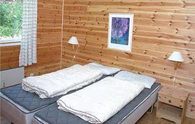 two beds in a room with a wooden wall at Stunning Home In Sandvoll in Sandvoll