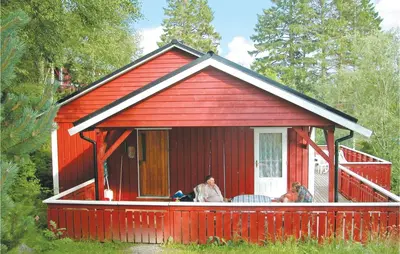 a red house with two people sitting on a porch at Nice Home In Sandvoll in Sandvoll