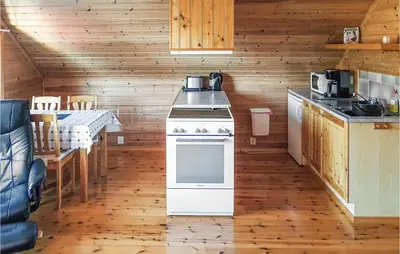 a kitchen with a stove and a table in a cabin at Holiday Home Finnås Lyklingsjøvegen in Vinnes
