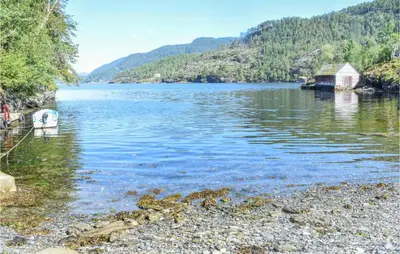 a body of water with a boat on the shore at Holiday Home Nordtveitgrend Nedrevågen in Hjartåker