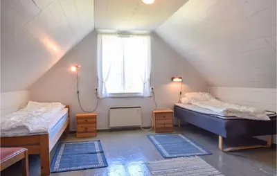 a attic room with two beds and a window at Holiday Home Nordtveitgrend Nedrevågen in Hjartåker