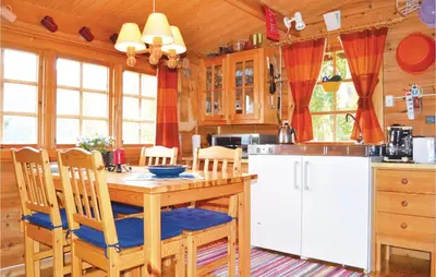 a kitchen with a wooden table with chairs and a refrigerator at Cozy Home In Norheimsund in Norheimsund