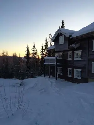 a house in the snow with the sun setting behind it at Nice apartment in Trysil ski in-out, sauna and view in Trysil