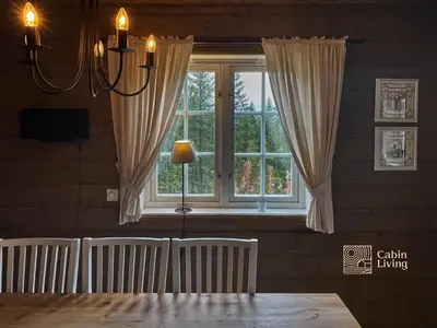a dining room with a large window with curtains at Nice apartment in Trysil ski in-out, sauna and view in Trysil