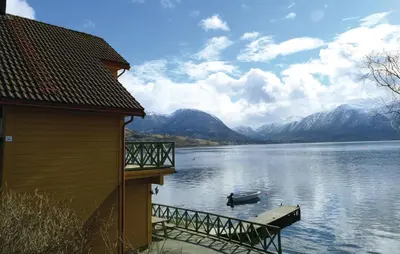 a boat on the water next to a house at Cozy Apartment In Rosendal With Sauna in Rosendal