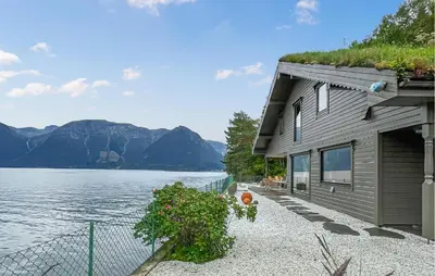 a house with a grass roof next to a body of water at Raaen Hytteutleige in Utne