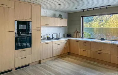 a kitchen with wooden cabinets and a large window at Raaen Hytteutleige in Utne