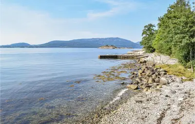 a rocky shore with a dock in the water at Eikhaugen Gjestegard in Husa