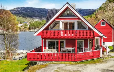 a red house with a red deck on a lake at Amazing Home In Nordtveitgrend in Hjartåker