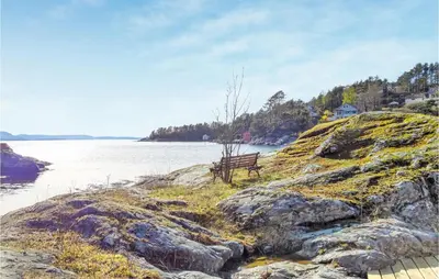 a bench sitting on the edge of a body of water at Amazing Home In Nordtveitgrend in Hjartåker