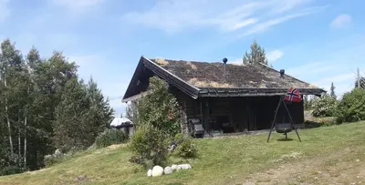 a house on a hill with a flag on it at Fredelig plass for rekreasjon in Krøderen
