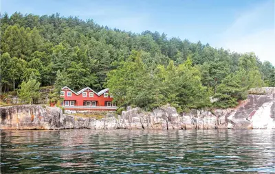 a red house on the shore of a body of water at Beautiful Home In Hatlestrand in Hatlestrand