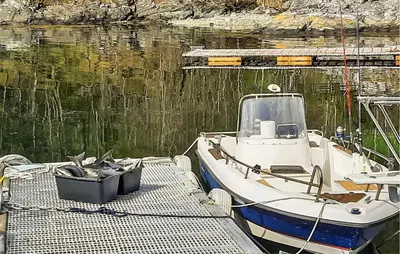 a boat tied up to a dock in the water at Lovely Home In Hatlestrand With Kitchen in Hatlestrand