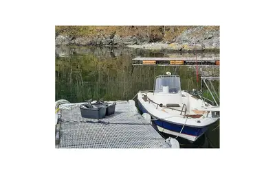 a boat is docked at a dock in the water at Cozy Home In Hatlestrand With Sauna in Hatlestrand