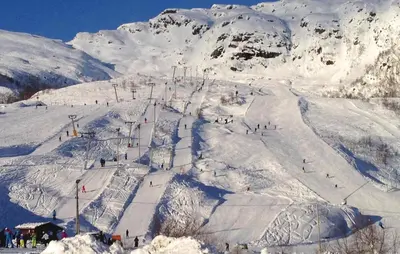 a snow covered mountain with people on a ski slope at Petterbua in Norheimsund