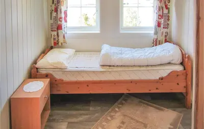 a wooden bed in a room with two windows at Holiday Home Jondal Torsnes in Jondal