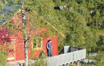 a man standing on a porch of a red building at Holiday Home Tysse Eikedal in Tysse