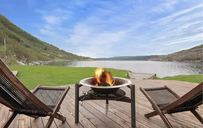 a fire pit sitting on a deck next to two chairs at Sørkvingo in Masfjorden