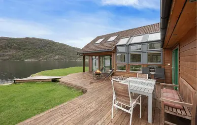 a house with a deck with a table and chairs at Sørkvingo in Masfjorden