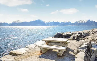 a bench sitting on the edge of a body of water at Cozy Home In Lavik With House Sea View in Lavik