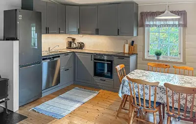 a kitchen with a table and chairs and a kitchen with gray cabinets at Cozy Home In Lavik With House Sea View in Lavik