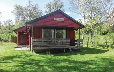 a red cabin in a field of green grass at Gorgeous Home In Ålfoten With Sauna in Ålfoten