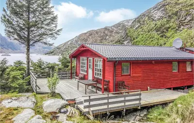 a red cabin with a wooden deck next to a lake at Holiday Home Måløy Husevåg in Måløy