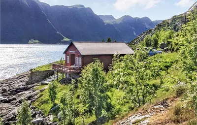 a small house on a hill next to a body of water at 3 Bedroom Awesome Home In Måløy in Måløy