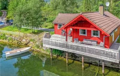 a red house on a dock with a boat on the water at 3 Bedroom Amazing Home In Sandane in Sandane